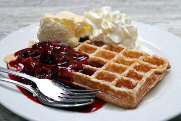 waffel mit vanilleeis, sahne und heissen kirschen