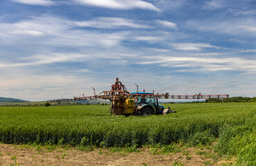 Tractor spraying oat field