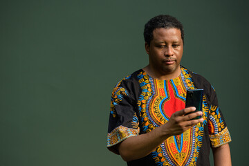 Portrait of handsome black man wearing traditional clothes and using mobile phone