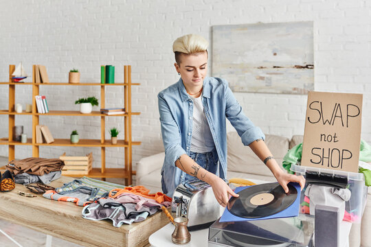collaborative consumption, smiling tattooed woman holding vinyl disc near record player, electric toaster, cezve, clothes and swap not shop card, sustainable living and circular economy concept