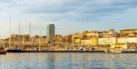 boats and yachts on pier in marine city port with masts and bulidings and blue sky on background , water cityscape of urban port