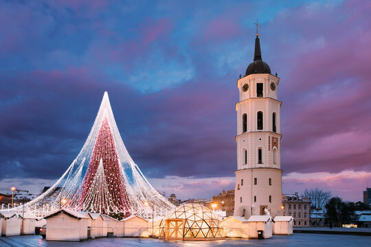 Vilnius, Lithuania. Amazing Magic Misty Cloud Colorful Sky Above Christmas Tree On Background. Bell Tower Belfry Of Vilnius Cathedral At Square In Evening New Year Christmas Xmas Illuminations.