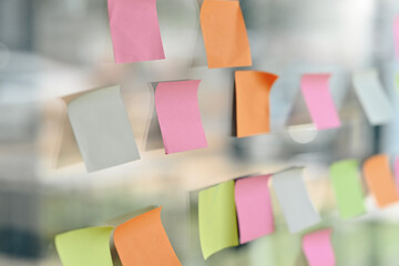 Closeup of colorful blank sticky notes, reminder paper note on glass wall in modern office