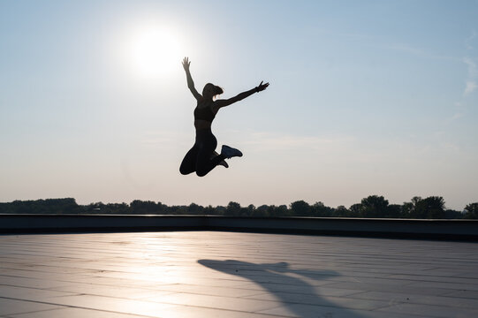 silhouette of a sport girl doing outdoors workout, girl jumping 
Sunny summer day