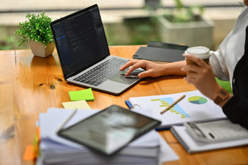 Cropped image of female programmer working with coded data on computer screen at her office