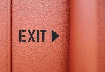 EXIT direction sign on orange wall - shows way out of public building - finding way out from...