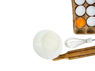 chicken eggs in an egg carton and a whisk and a plate with flour on a white background, copy space, Cooking dough