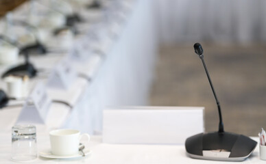 Conference microphone system on a white table with notebooks in background. Concept image for office meetings.