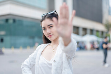 A stern young woman say no, gesturing to stop with her open palm. Rejecting an offer or feeling...