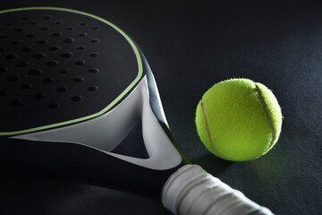 Detail of black padel racket and ball on black background