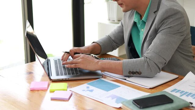 Man working in the office, startup company employee working attentively, he is summarizing work to bring information to executives to see and analyze to develop the company to grow.