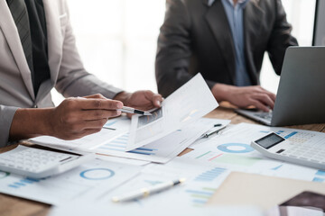 Close up group of business men and woman discussion and brainstorming, bookkeeping audit graph and chart documents at desk, teamwork concept.