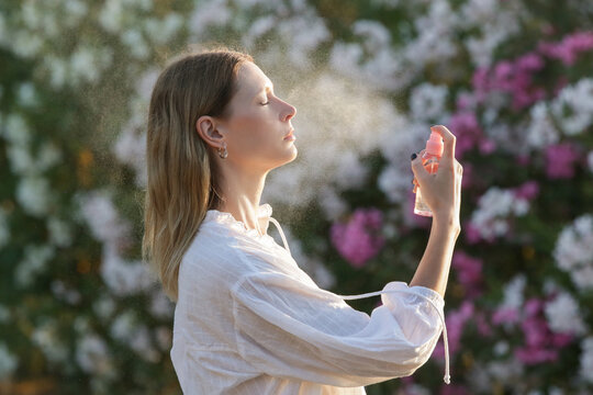 Woman spraying facial mist on her face, summertime skincare concept