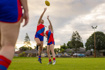 two female football players jumping for the ball at training