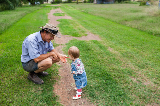 Toddler with farmer looking at rocks on driveway on farm property