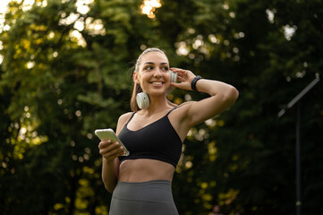 Sport girl listening music on headphones, while prepairing for outdoor running