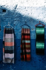 Scarfs on vibrant blue wall: Colorful scarfs adorn a captivating blue backdrop, creating a visually dynamic display.