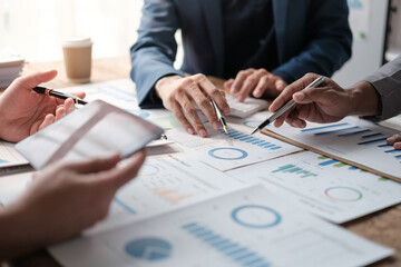 Close up group of business men and woman discussion and brainstorming, bookkeeping audit graph and chart documents at desk, teamwork concept.