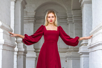 Portrait of a young beautiful blonde girl in an evening burgundy dress