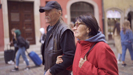 Elderly couple of tourists are walking through the historical center seeing the sights in an old...