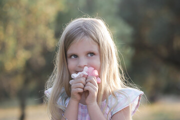 Cute little girl smelling flowers in the park