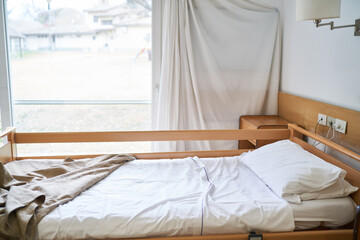 Fototapeta na wymiar Blanket and pillow on empty bed in rehabilitation center