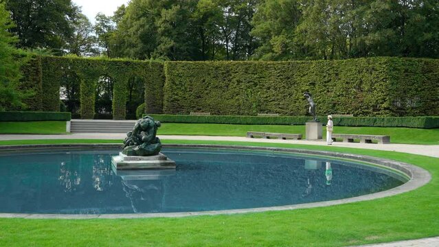 Young girl walking in the garden by the pool with sculpture outdoors