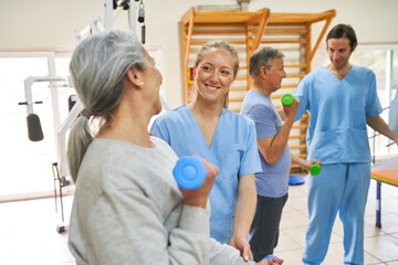 Female nurse assisting elderly woman exercising with dumbbells