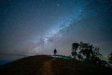 Naklejka na ściany i meble A man standing in the top of mountain with plenty of star in the sky (Chiang mai province, Thailand). amazing natural landscape. popular attractions best famous tourist attractions