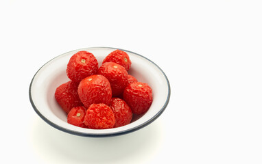 Pile of rotten tomatoes is on a bowl over a white background.