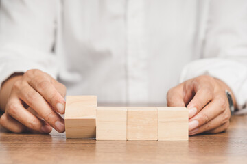 Business people hold four blank wooden cubes while sitting at the table.