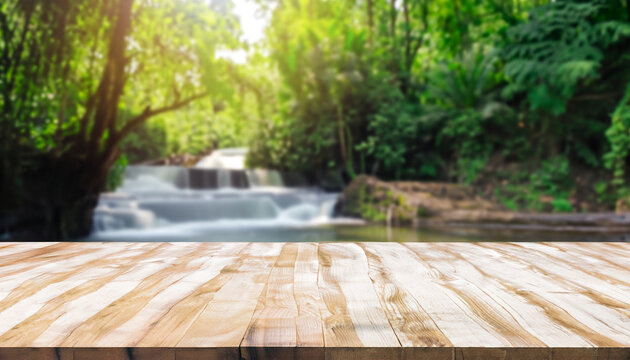 Wooden table top on blur stream and forest natural background in waterfall. For montage product display or design key visual layout. view of copy space.