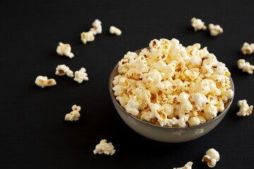Homemade Buttered Popcorn with Salt in a Bowl on a black background, low angle view.