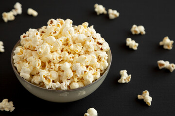 Homemade Buttered Popcorn with Salt in a Bowl on a black background, low angle view.