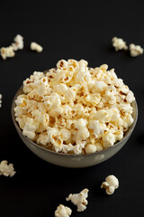 Homemade Buttered Popcorn with Salt in a Bowl on a black background, low angle view.