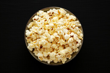 Homemade Buttered Popcorn with Salt in a Bowl on a black background, top view. Flat lay, overhead, from above.