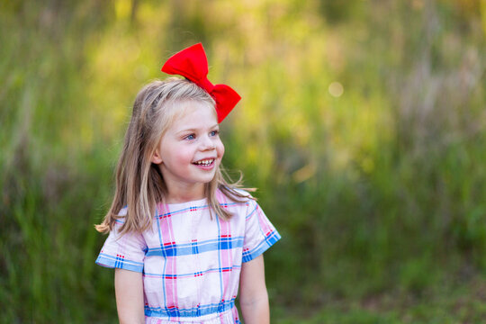 Happy young girl with red hair bow looking to the side with copy space