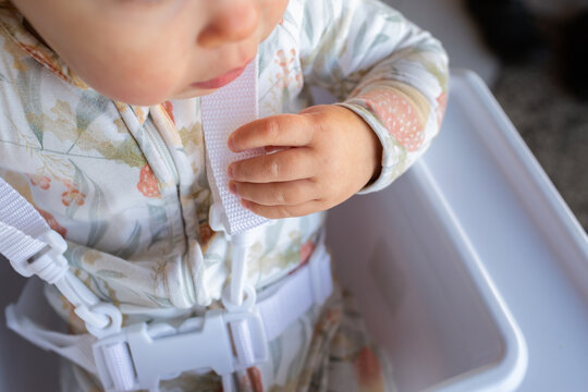 Baby safety - child holding onto seatbelt buckle straps in high chair