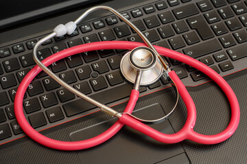 Medycyna online, telemedycyna stetoskop czerwony medyczny leżący na laptopie