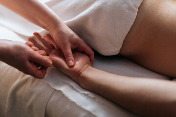 Close-up cropped shot of unrecognizable professional masseuse hands doing finger and palm massage...