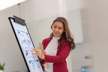 Female office worker working on her presentation standing near white board the profit report finance