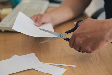 Left-handed man's hand cutting paper with scissors wave