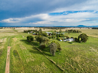 Farm house with garden in home paddock of large property with distant rain