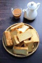 Tea Time Snack. Healthy Wheat rusk served with Indian hot masala tea and milk jug over black background. also known as Mumbai cutting chai. with Copy space. Crunchy rusk or toast.