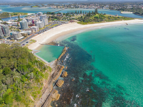 Distant aerial view of an ocean bath in front of a long beach and a river in the distance