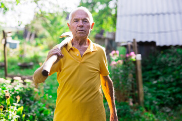 Obraz premium Old man standing in backyard with shovel in hand