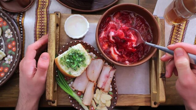 Traditional Ukrainian dish Borscht. Eating red Ukrainian borscht from first person POV. A hand stirs the first course of beetroot with a spoon.