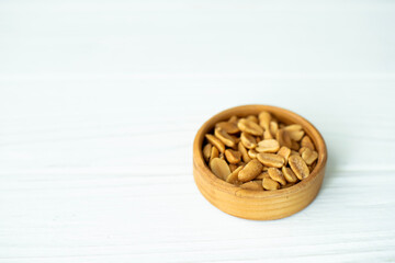 Peanuts in a wooden plate on a white background