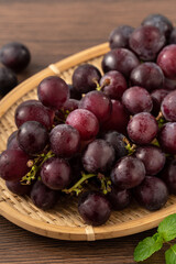 Delicious bunch of grapes fruit on a plate over wooden table background.
