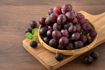 Delicious bunch of grapes fruit on a plate over wooden table background.